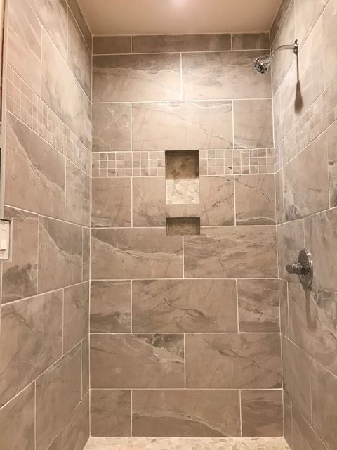 Tiled shower stall with recessed niches and pebble tile floor