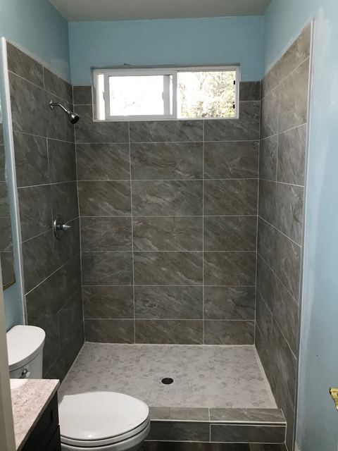 Tiled shower with window, viewed from adjoining bathroom
