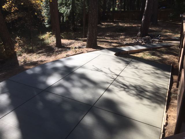 Freshly poured concrete patio slab in a wooded backyard