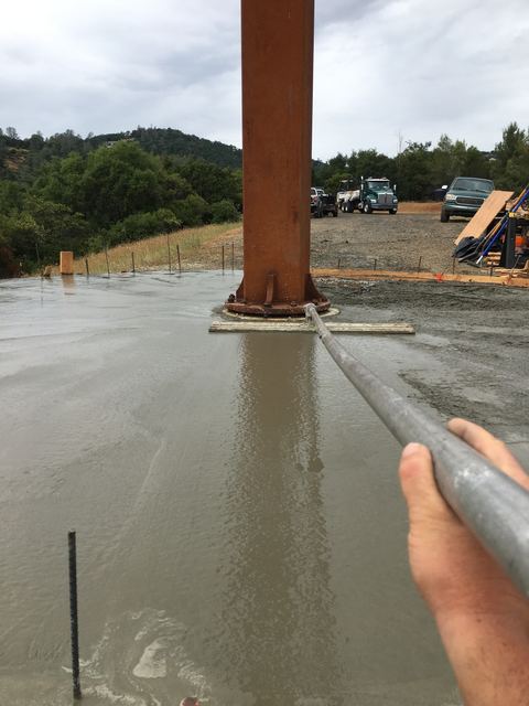 Freshly poured and finished concrete slab around a steel support post