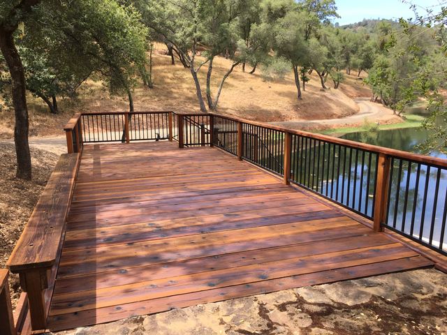 Elevated wood deck with metal railing overlooking a pond