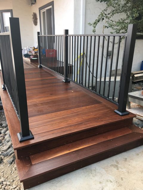 Wood deck with built-in steps and metal railing beside a stucco house
