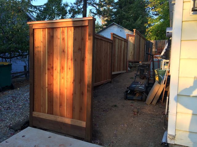 Cedar privacy fence panels running along a side yard at dusk