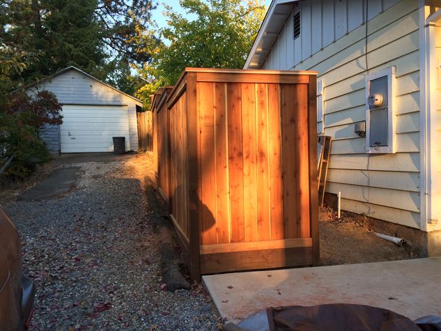 Cedar fence panel detail beside house siding and electrical meter