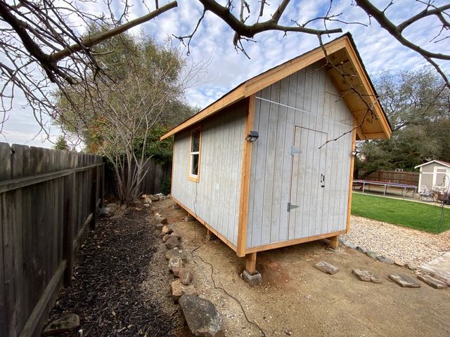 Backyard shed side view showing window and raised foundation piers