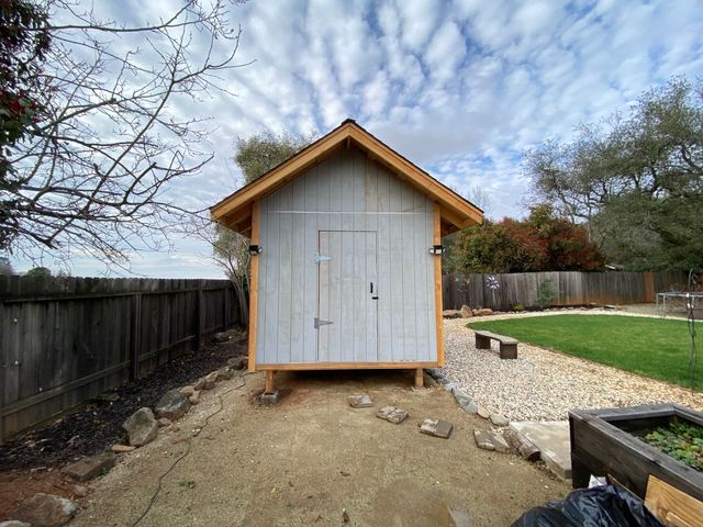Backyard shed front elevation with stone border landscaping