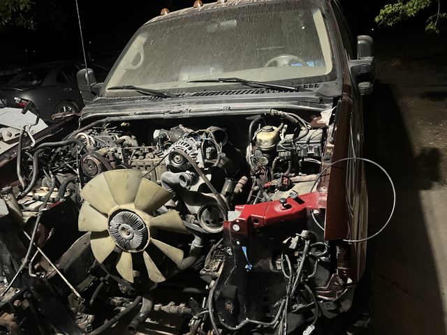 Truck engine bay with engine partially disassembled at night