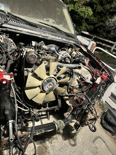 Truck engine bay teardown in daylight showing fan clutch and wiring