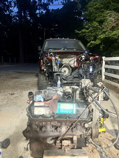 Removed truck engine set up on a stand in front of the empty engine bay